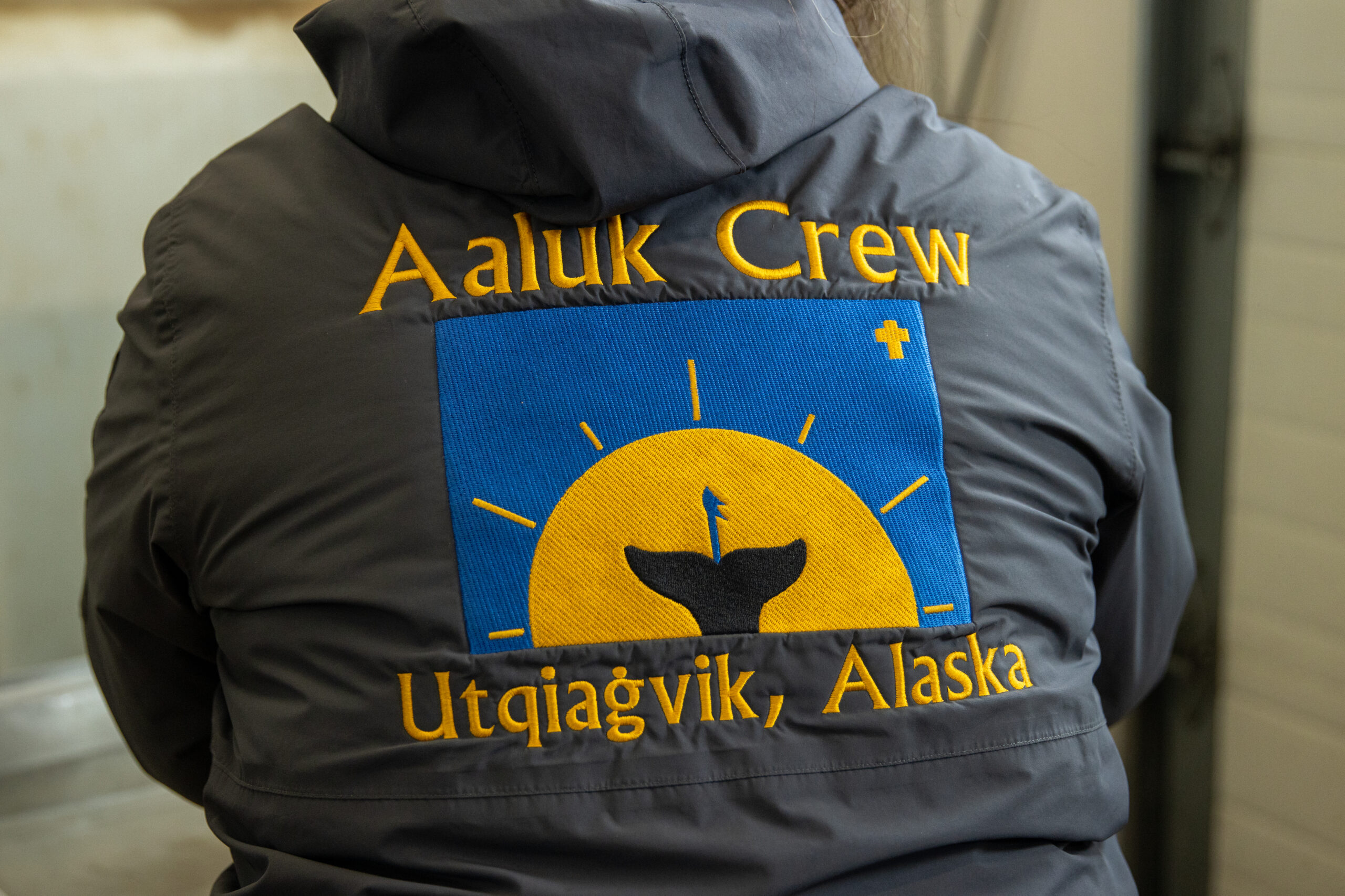 A yellow and blue logo on the back of a hoodie reads "Aaluk Crew Utqiagvik, Alaska"