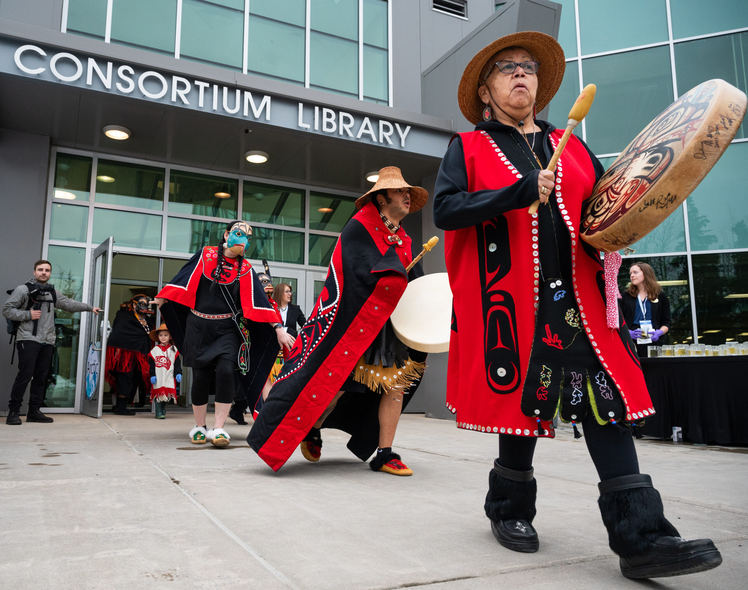A Tlingit dance group performs in front of an entryway.