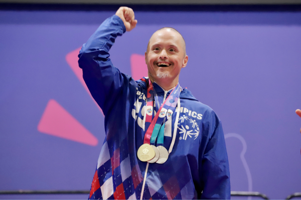 A man stands with multiple Special Olympics medals.