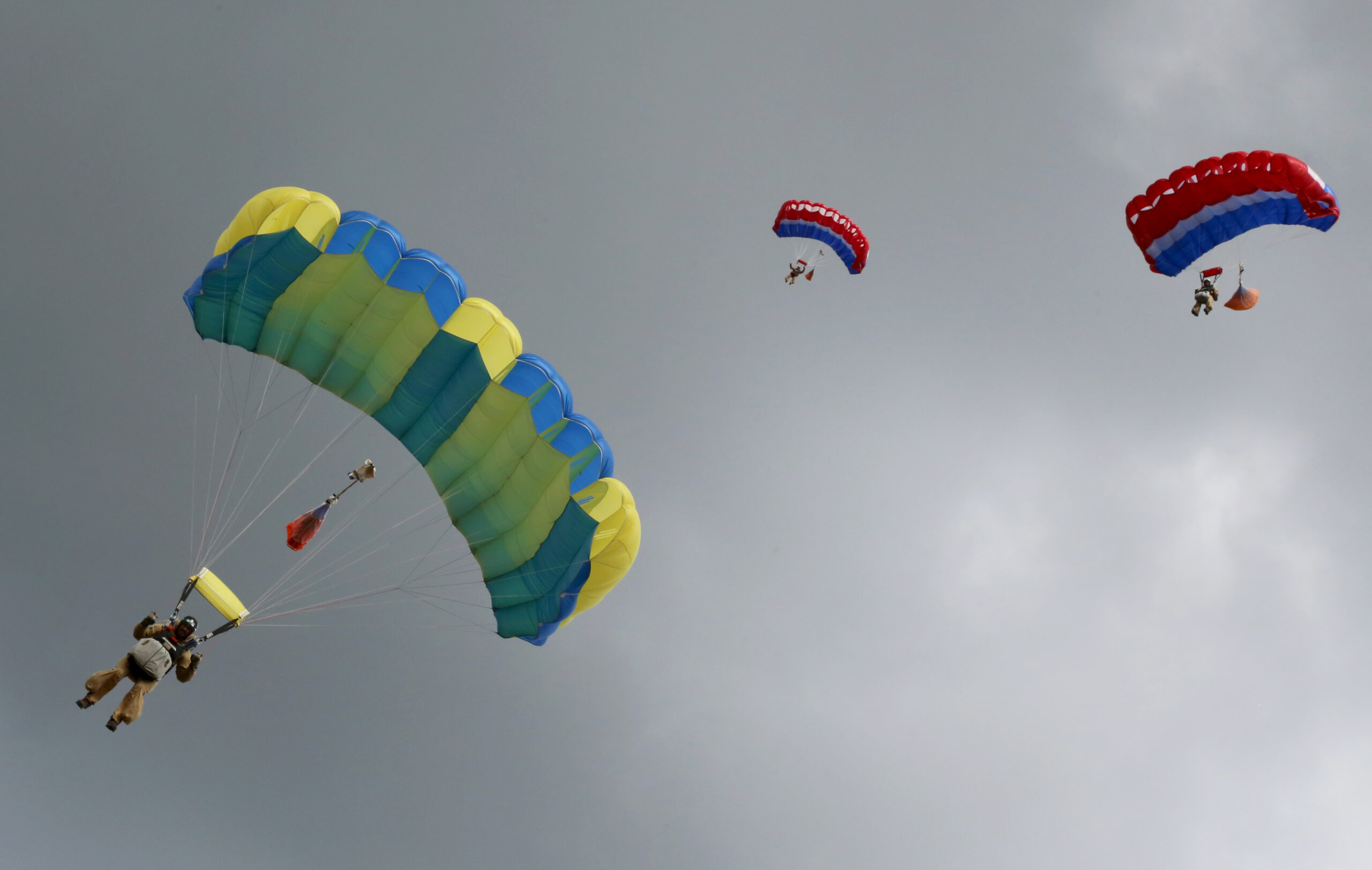 Three parachutists descend toward the camera.