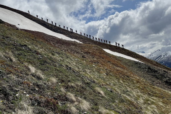A line of hikers ascend a ridge.