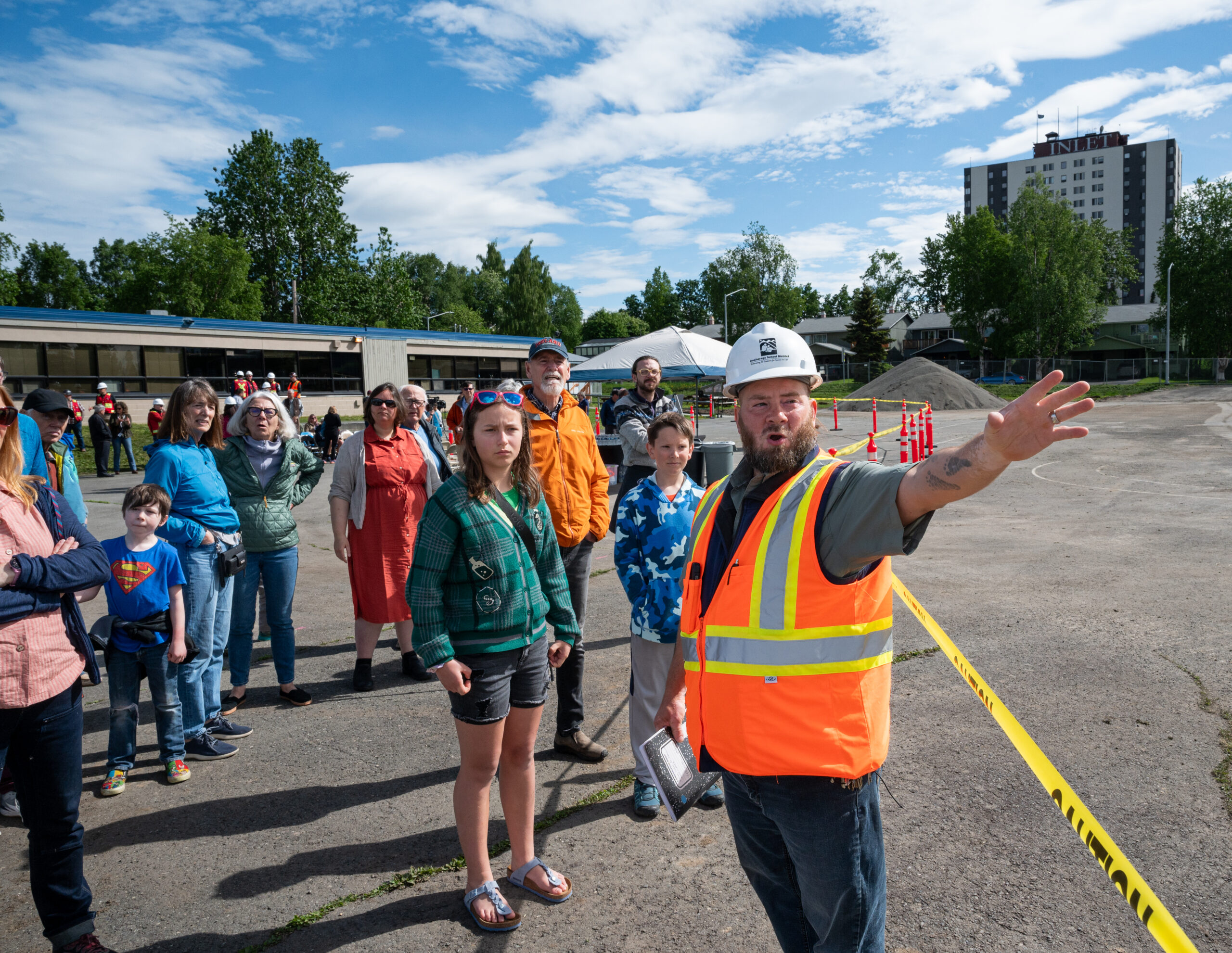 A project manager in an orange safety vest and helmet gives a tour.