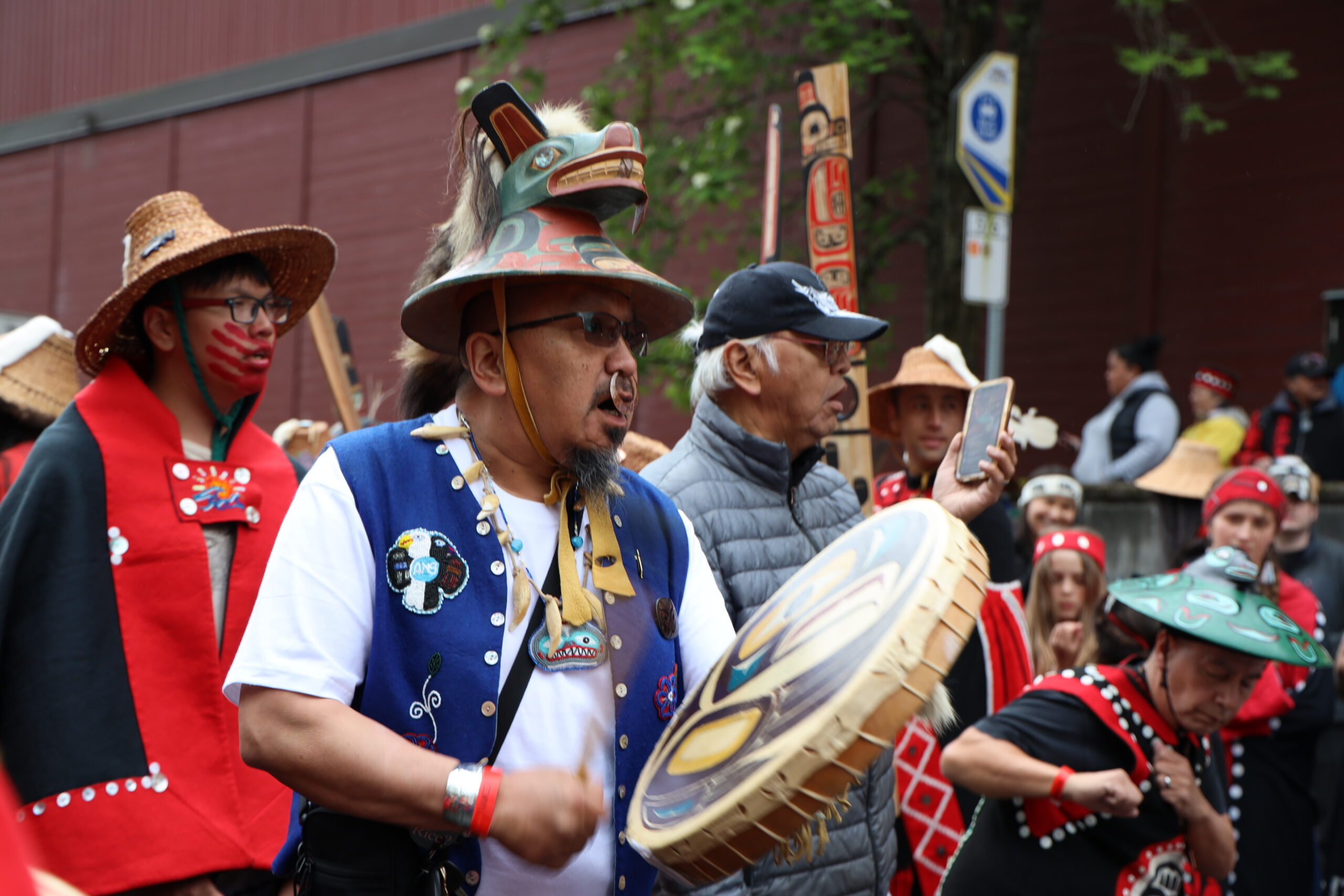 a group of people drum and sing in the street for a celebration