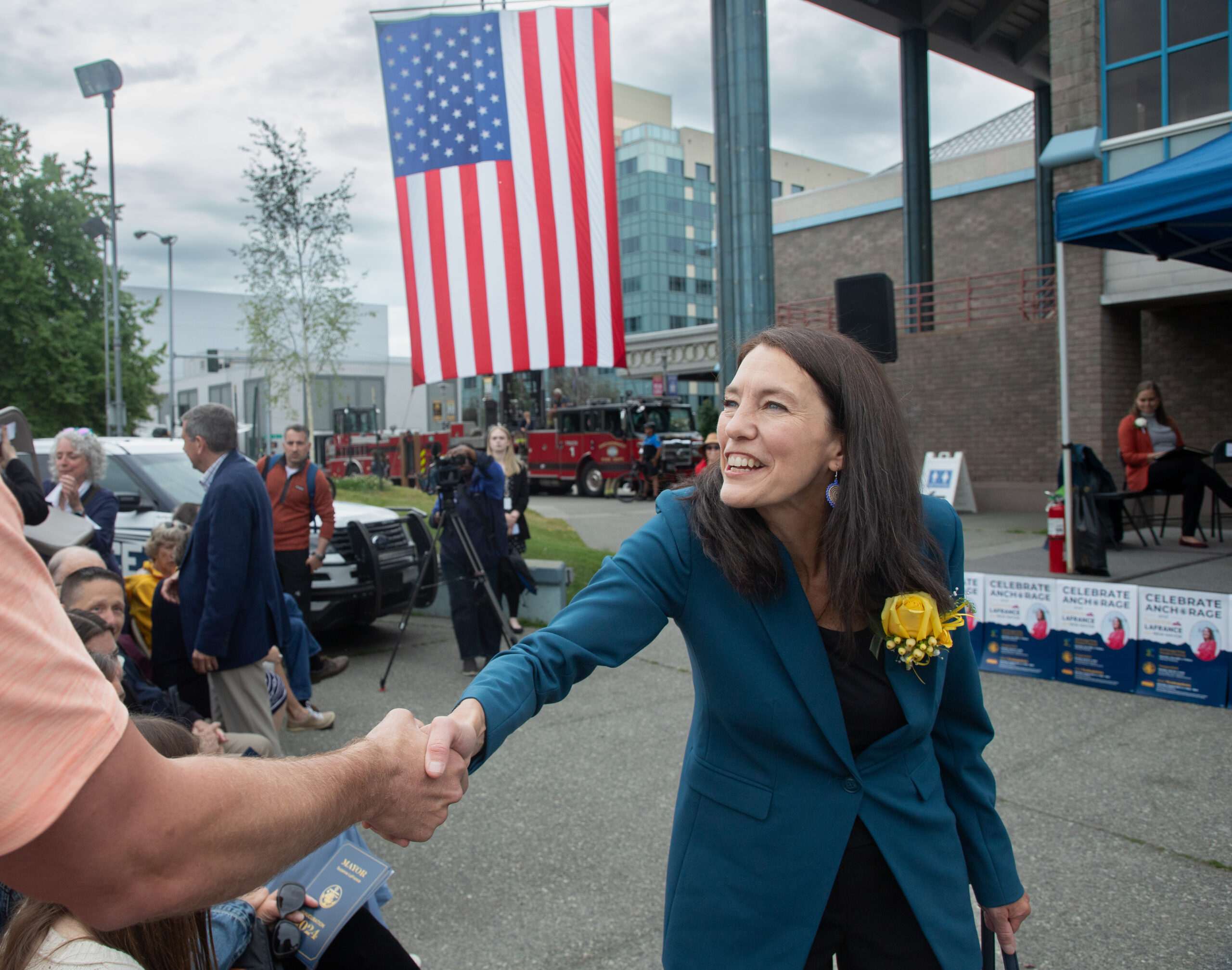 A woman in a blue suit shakes hands with people.