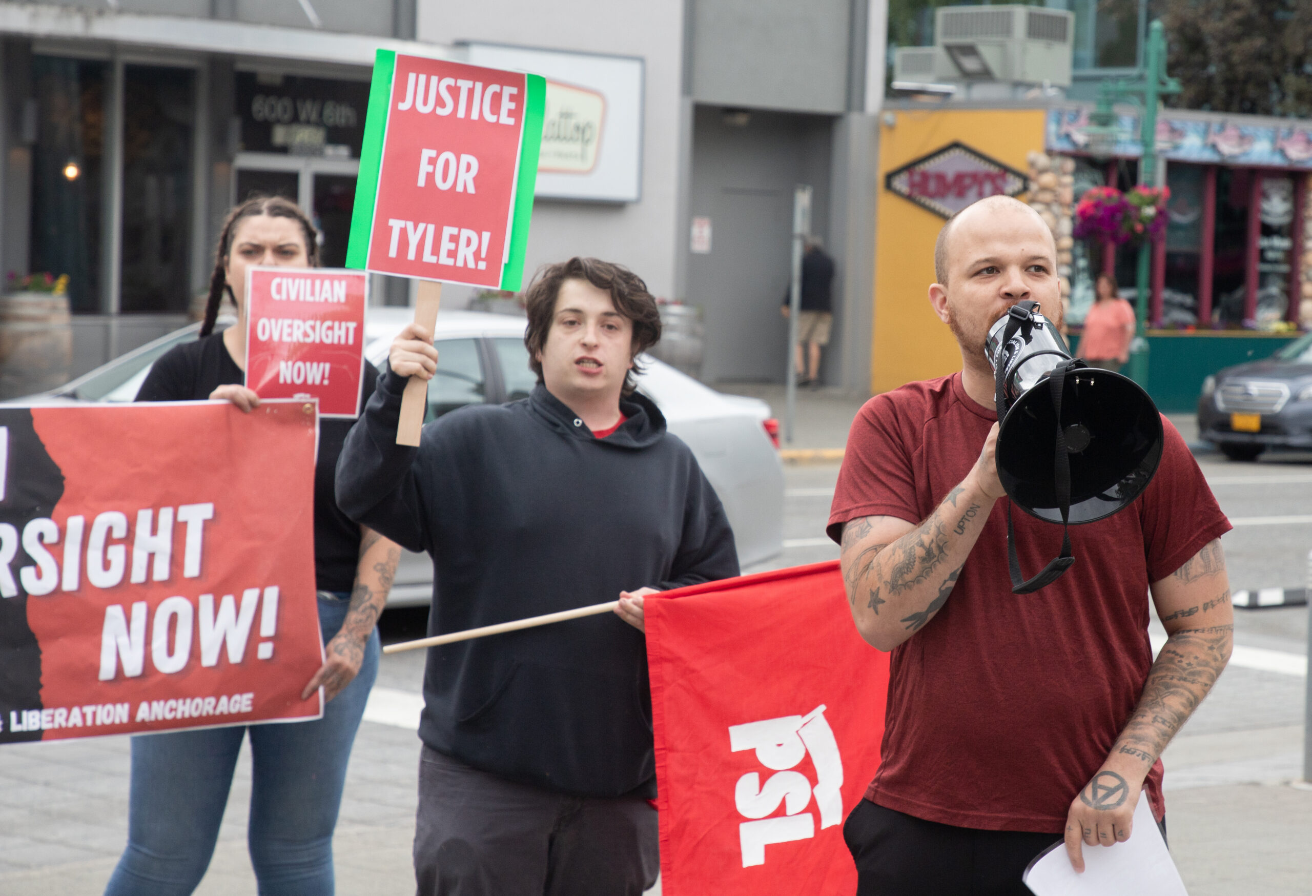 A man successful a reddish garment speaks into a a achromatic megaphone.