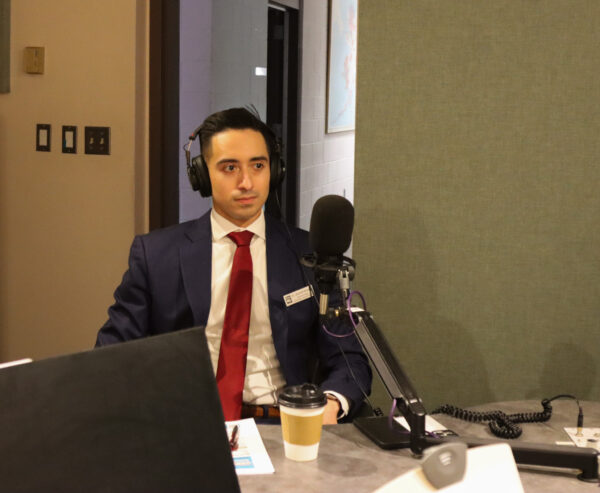 A man in a suit sits in a radio station.