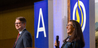 a woman laughing and man standing next to her