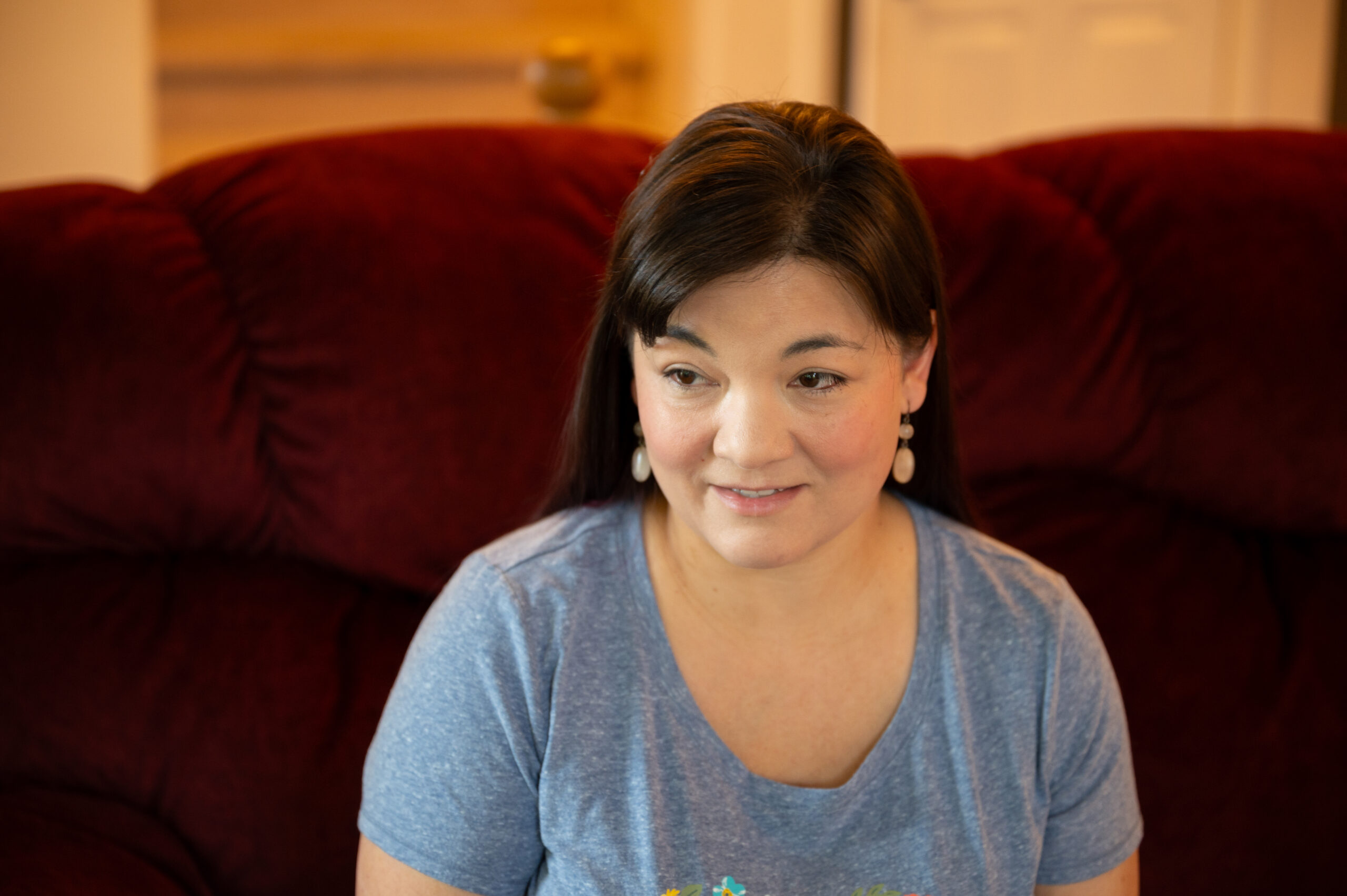 A woman sits on a red couch.