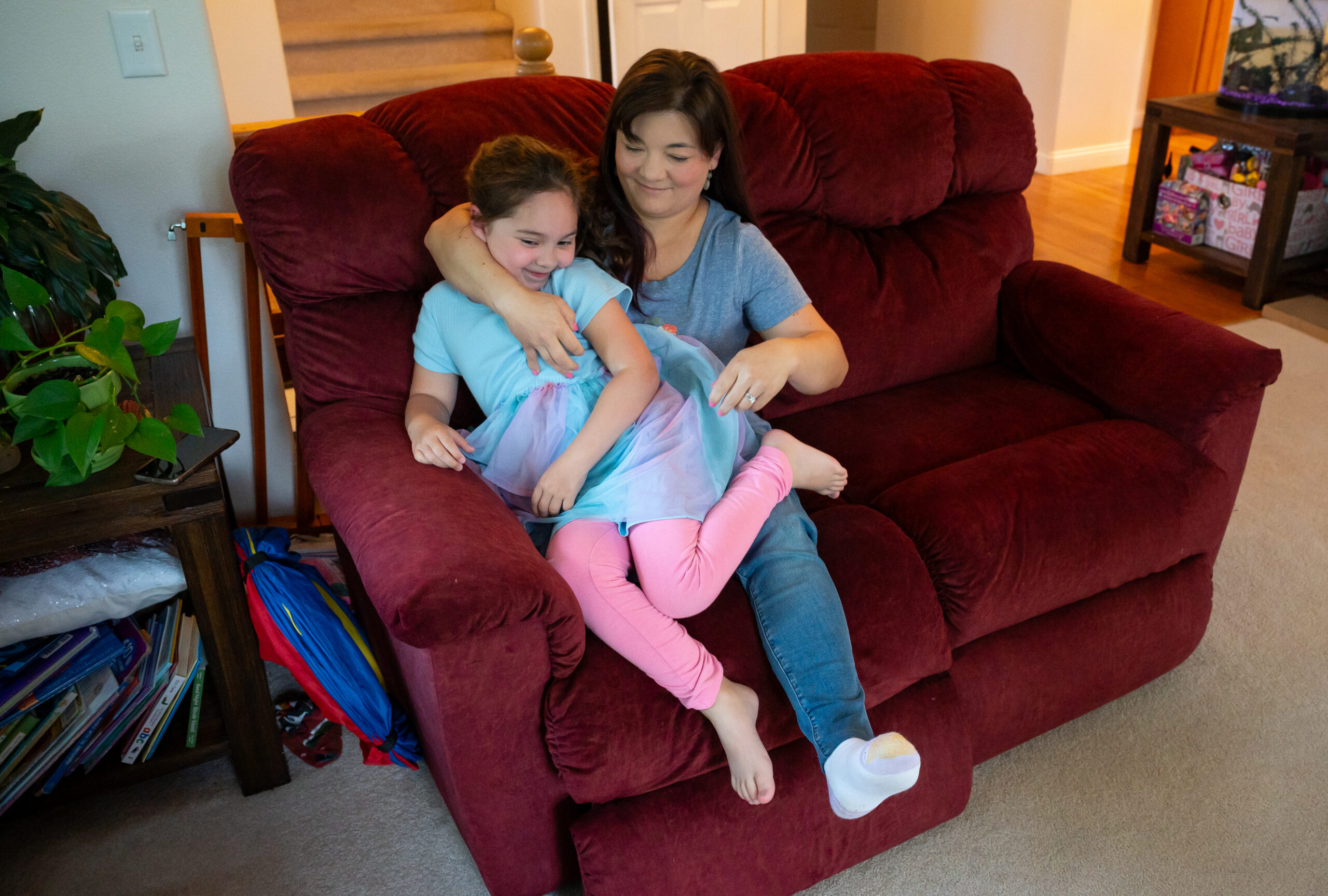 A woman plays with her daughter on a couch.