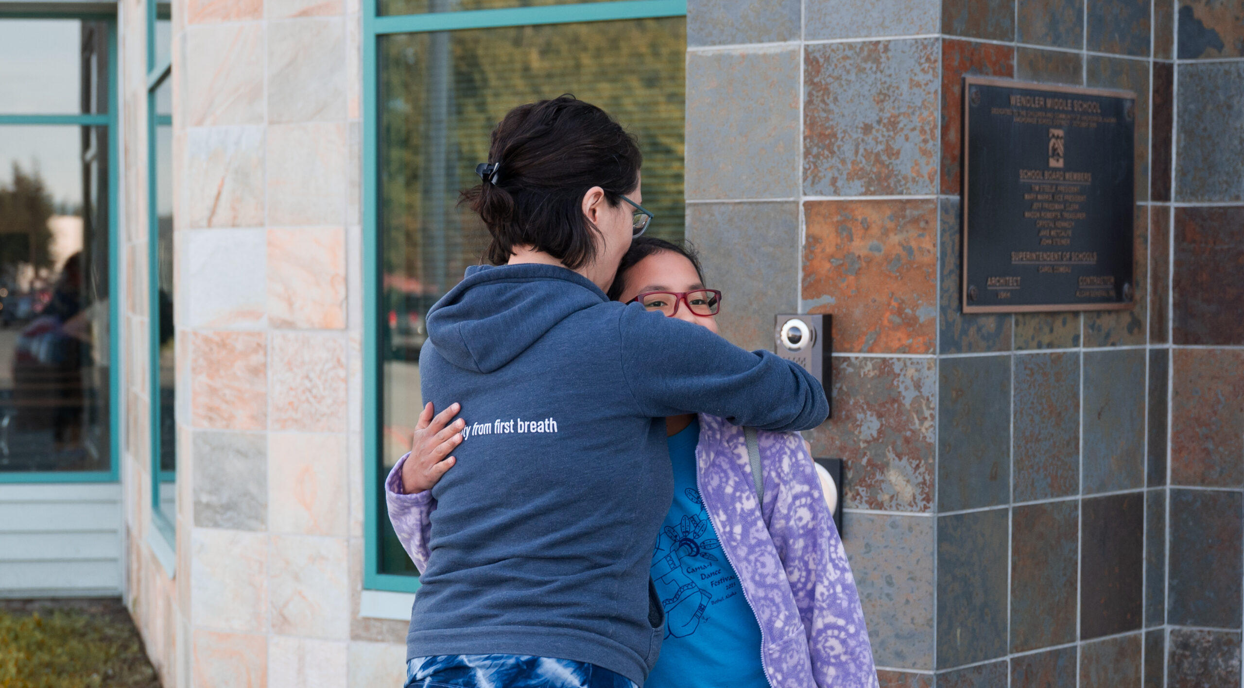 A Mom hugs her daughter.