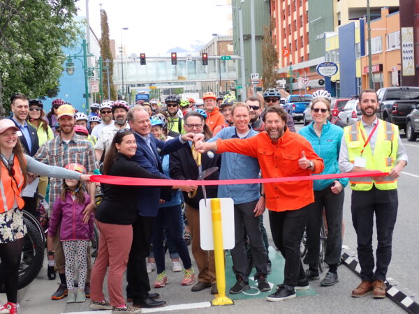 A group of people cut a ribbon in downtown Anchorage.