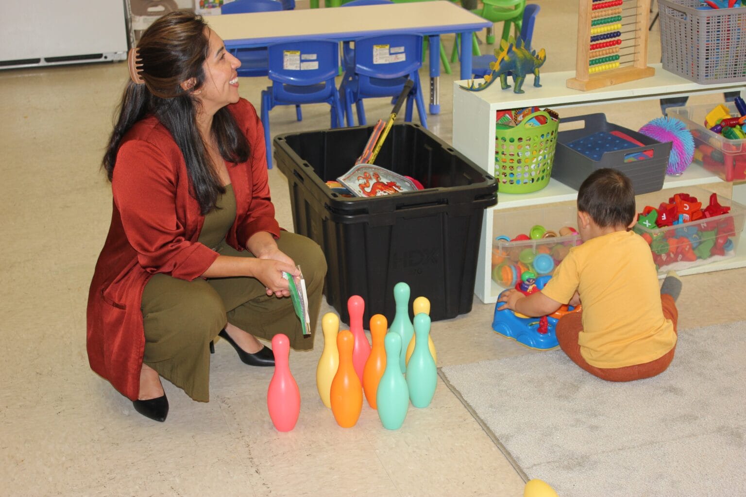 an adult and a child playing with plastic bowling pins