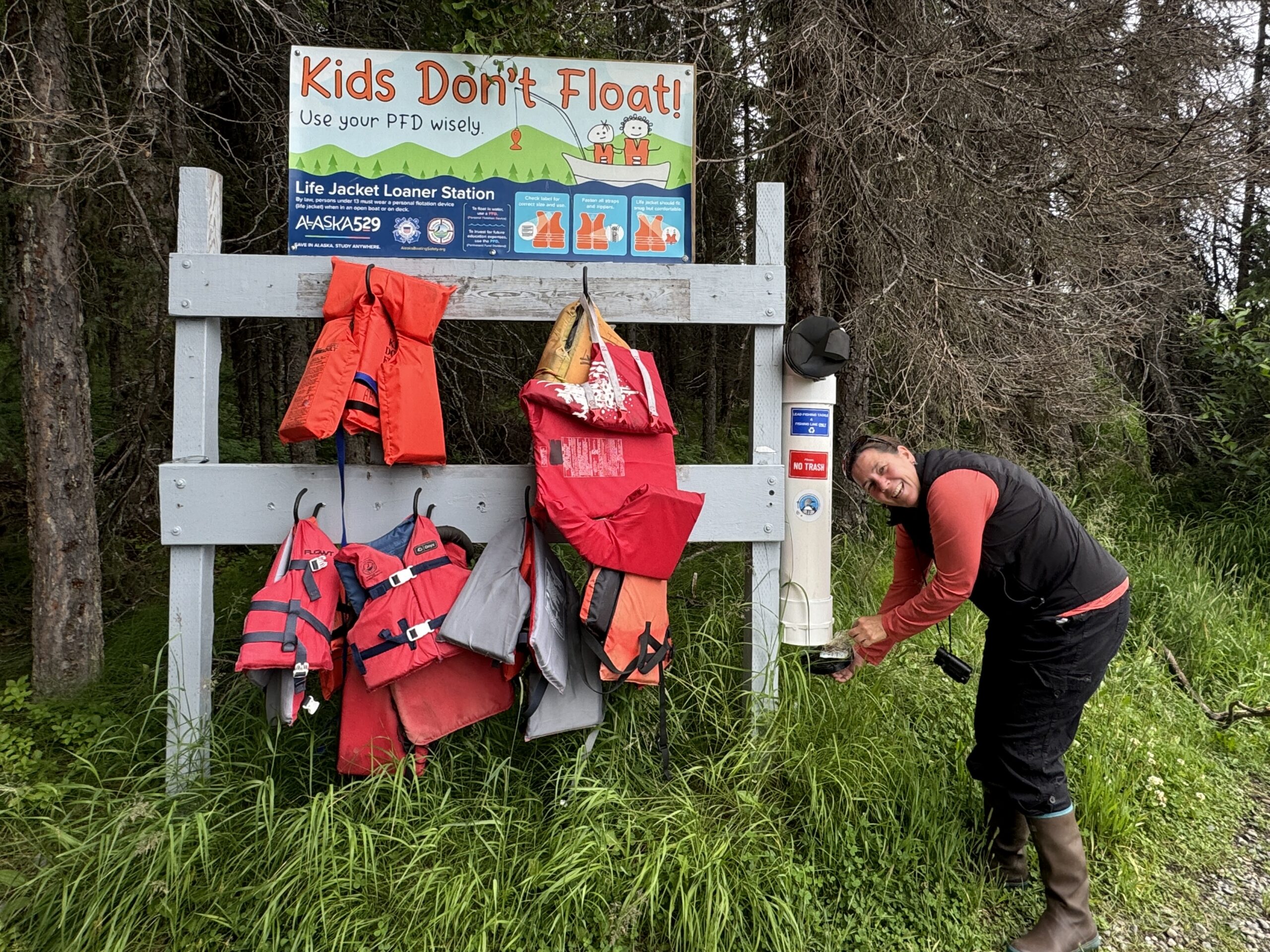 A female pulls sportfishing statement from a postulation constituent adjacent to a rack of life jackets. 