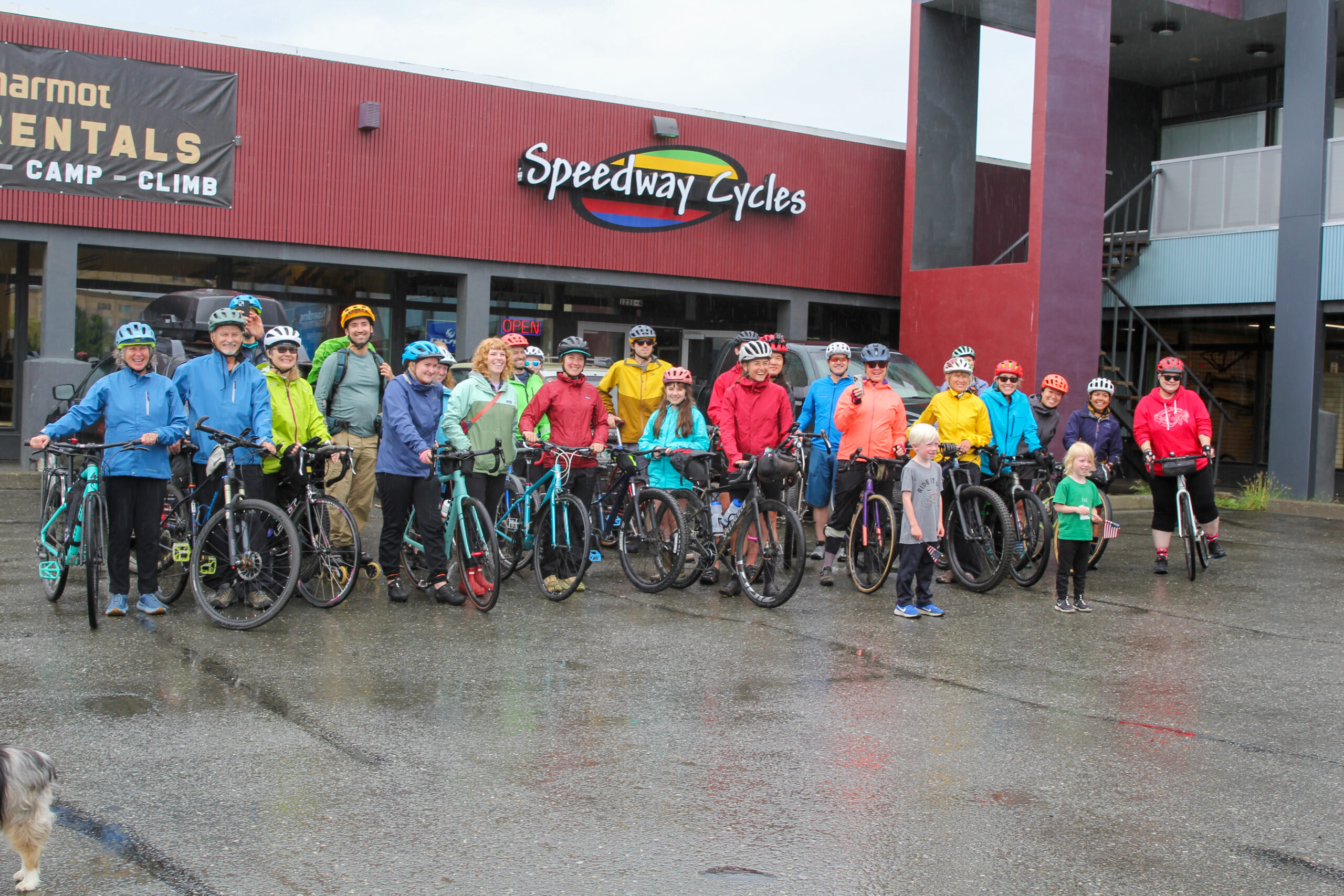 dozens of group station for a photograph successful rainfall jackets and helmets nether a storefront that says "speedway cycles"