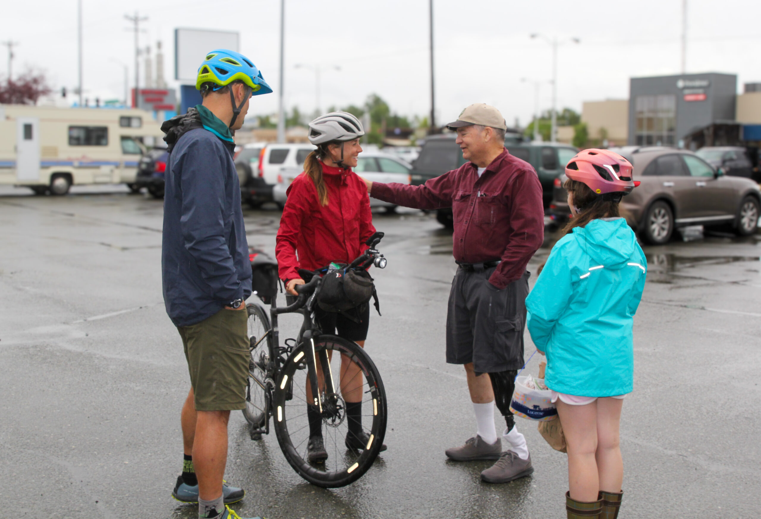 two men and 1 young woman guidelines astir Lael Wilcox, who is opinionated pinch her motorcycle adjacent to her.