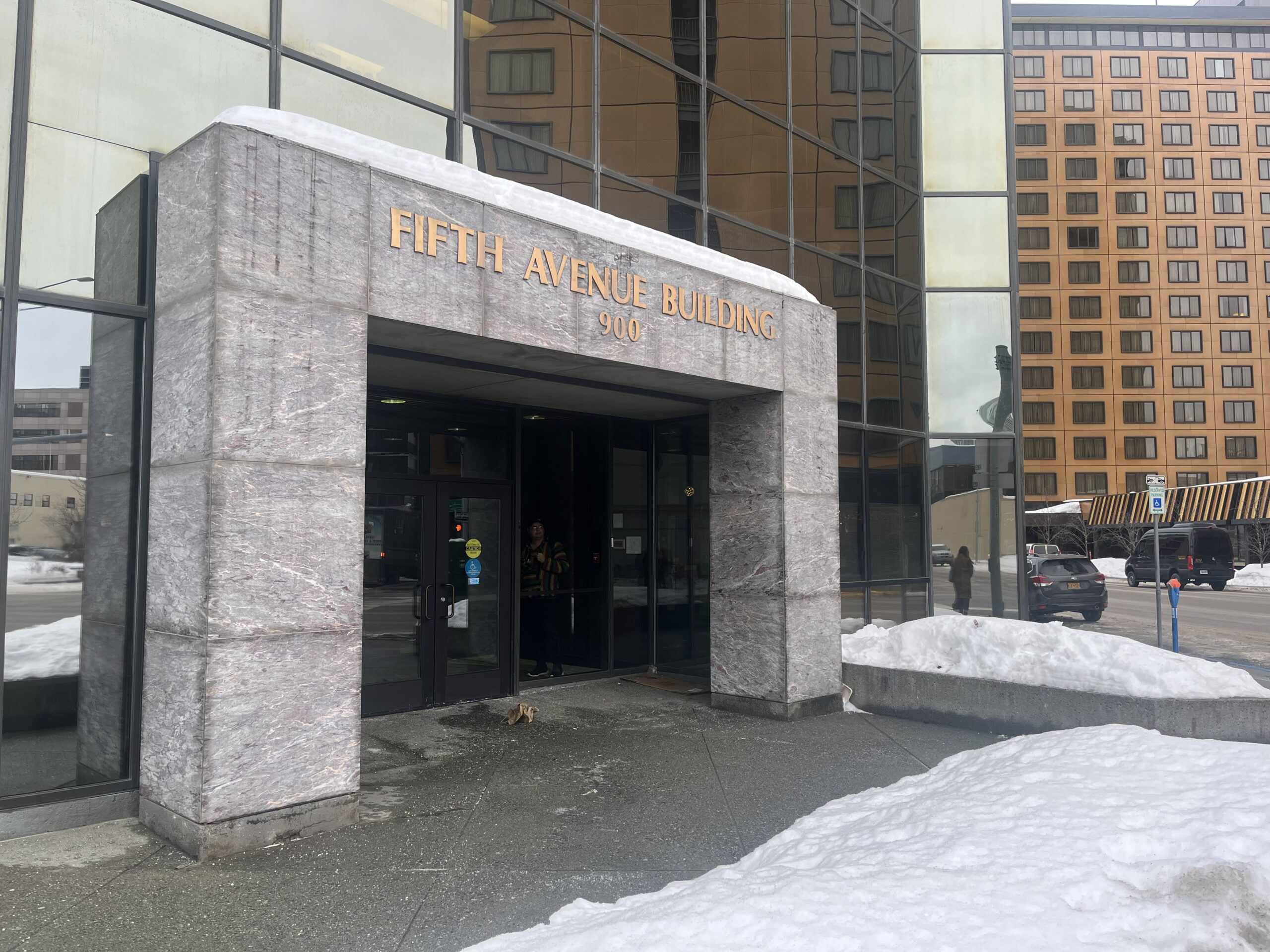 Stone building entrance with gold letters that say "Fifth Avenue Building."