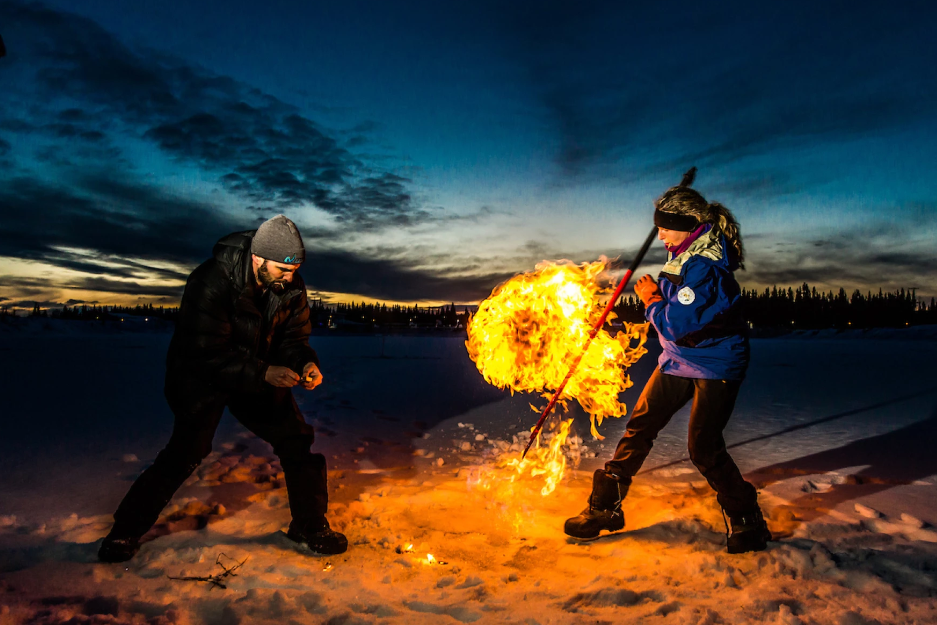 A woman holding a pole is near a fireball.