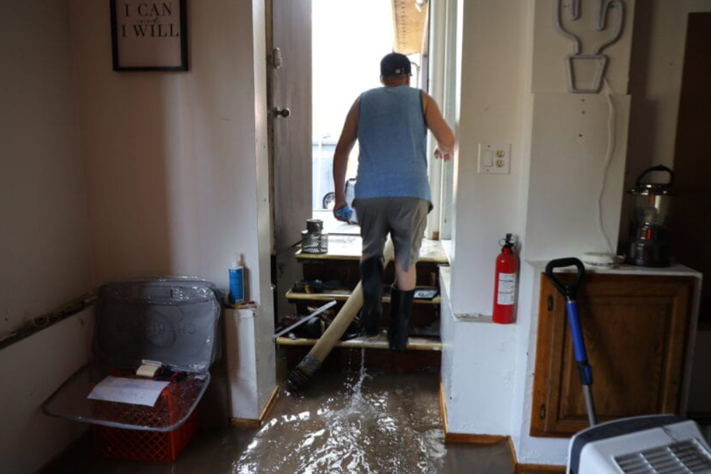 A man walks up a group of stairs arsenic h2o pours into his home.