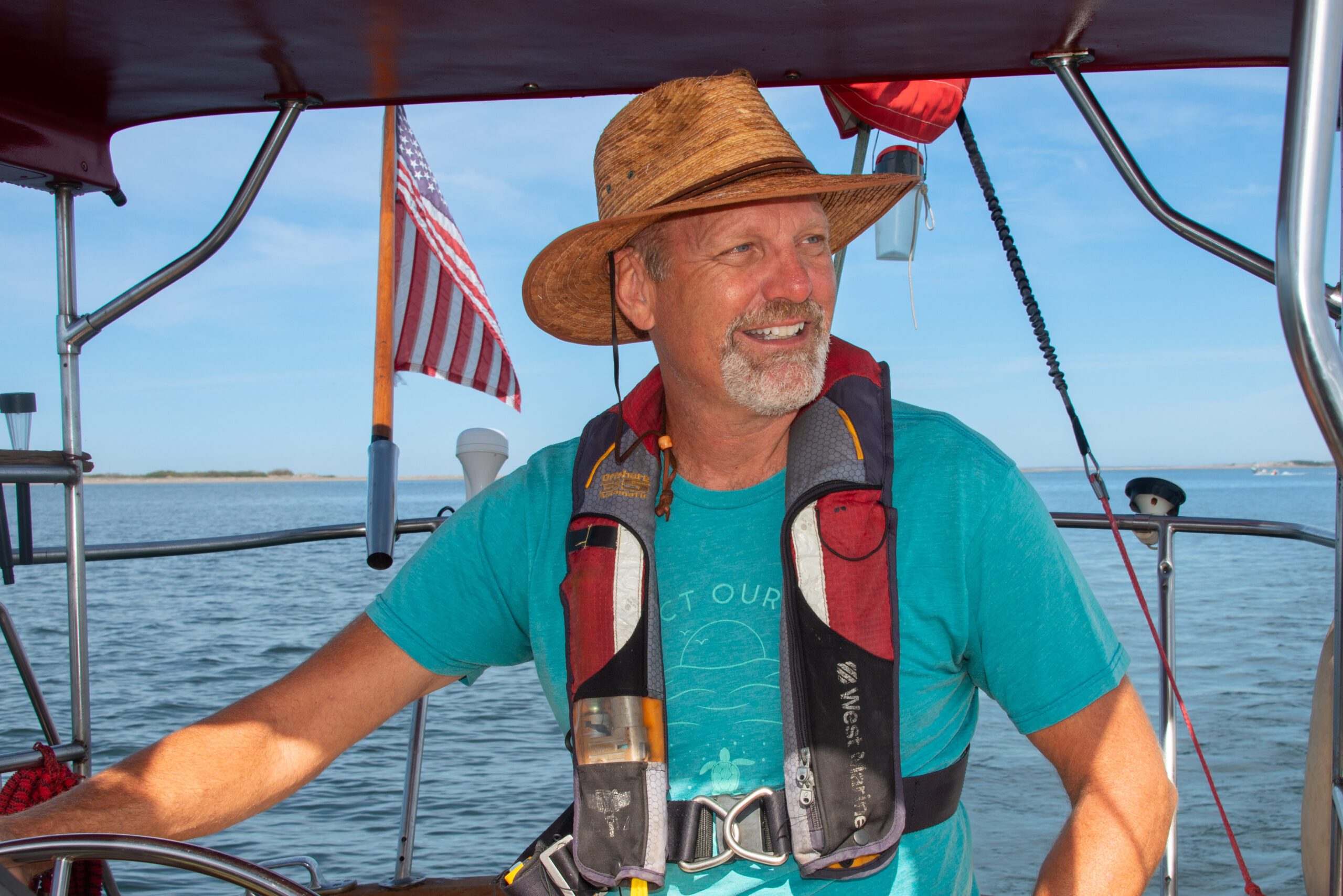 Bill Streever smiles and looks into the distance while sailing a boat.