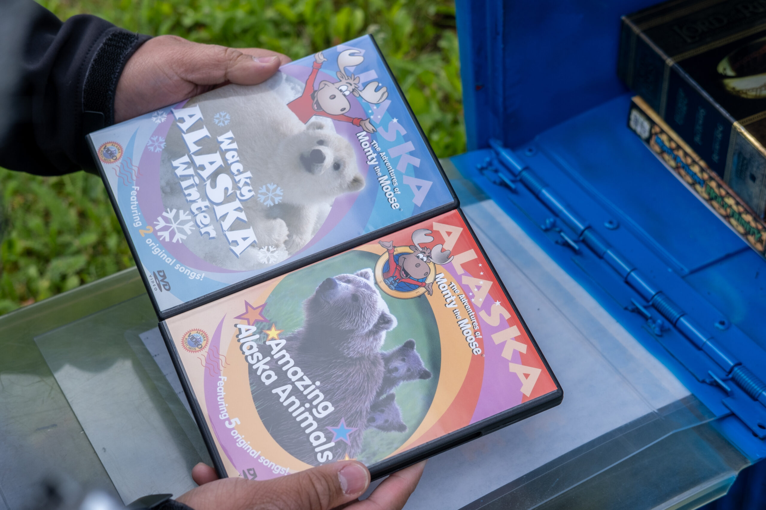 a close up on two hands holding two DVD cases. one says "wacky alaska winter" the other says "amazing alaska animals"