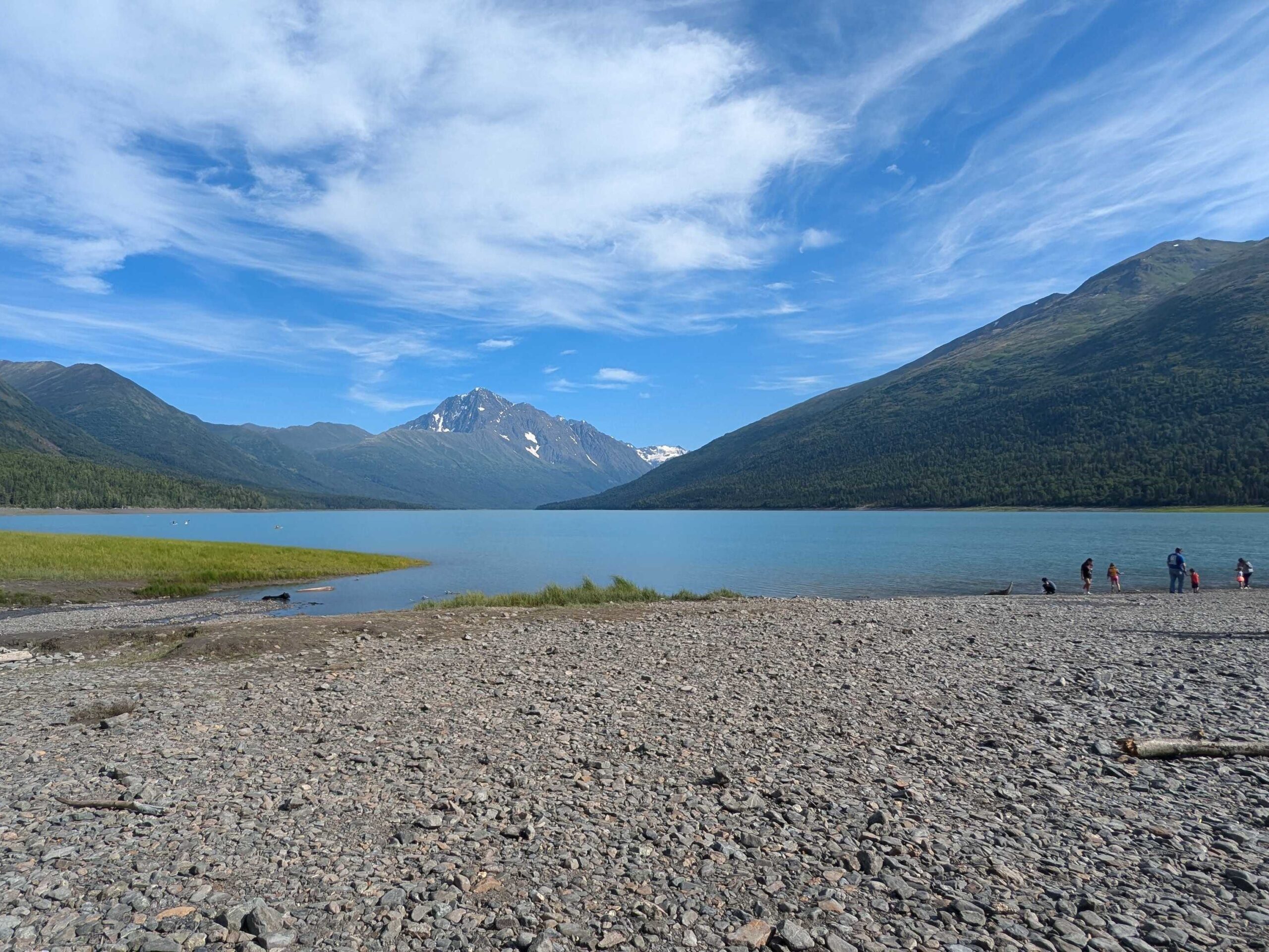 a gravel beach by a lake among mountains