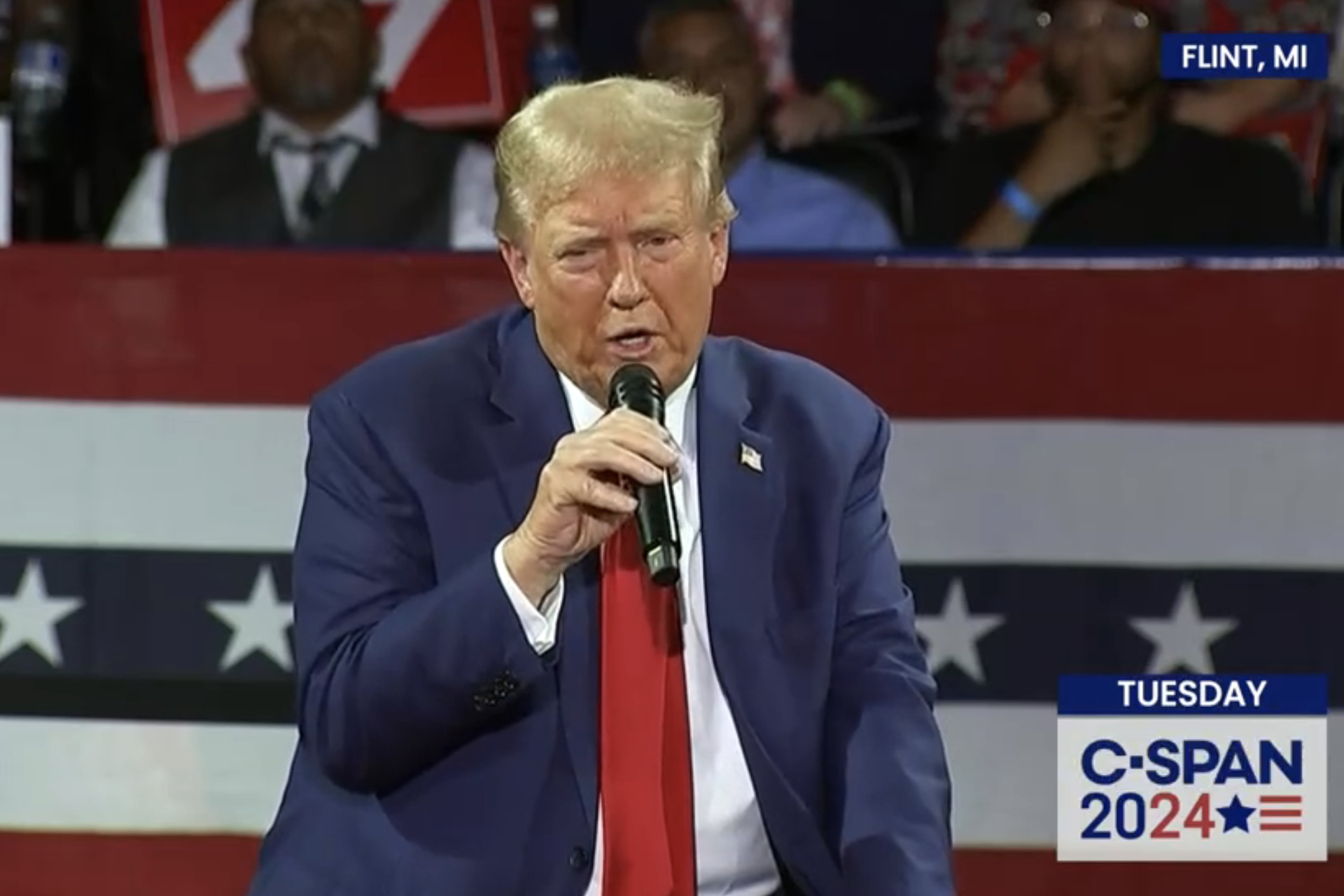 man successful suit and reddish necktie holds mic