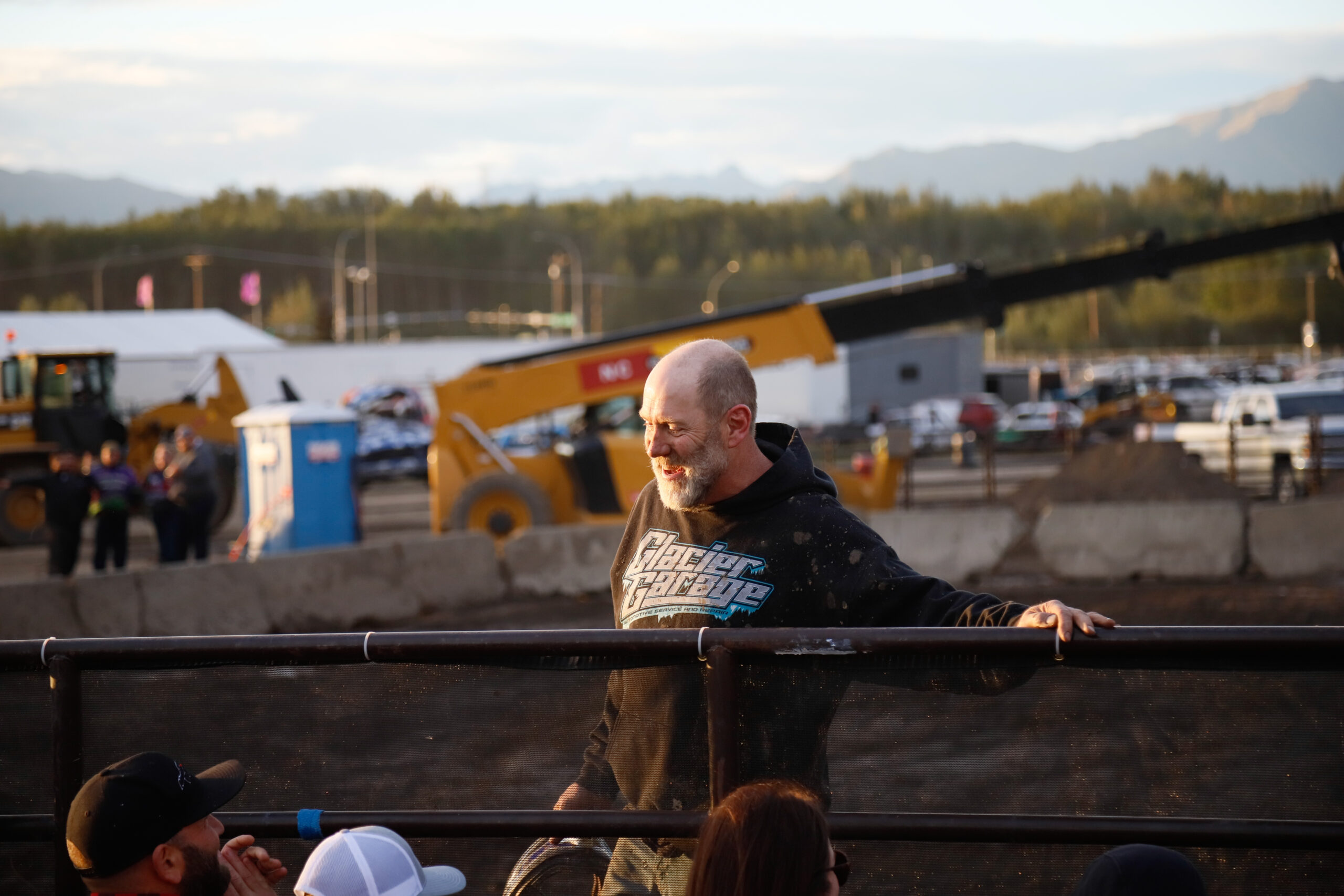 a smiling man stands behind a guard rail.