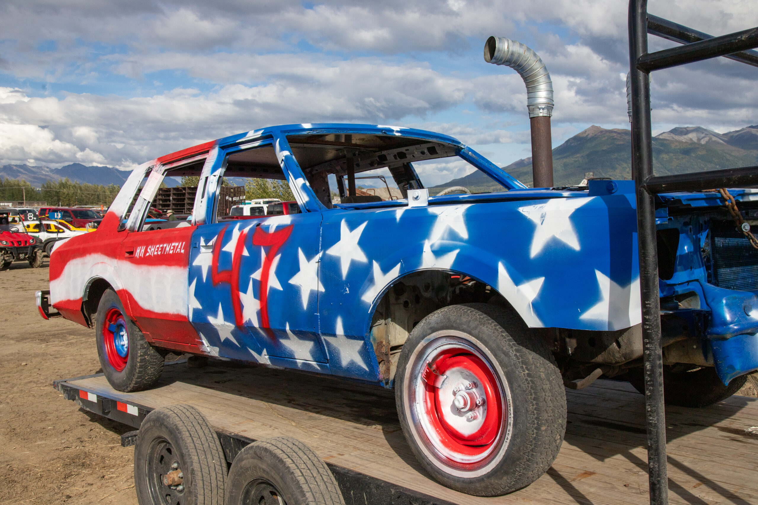 a car is painted with red and white stripes on one half, and blue with white stars on the other half. it says 47 on the door