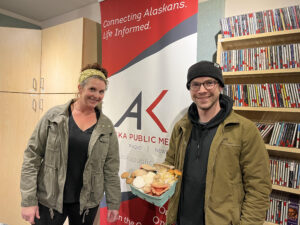 A man and a woman pose in a radio studio with a basket of mushrooms. 