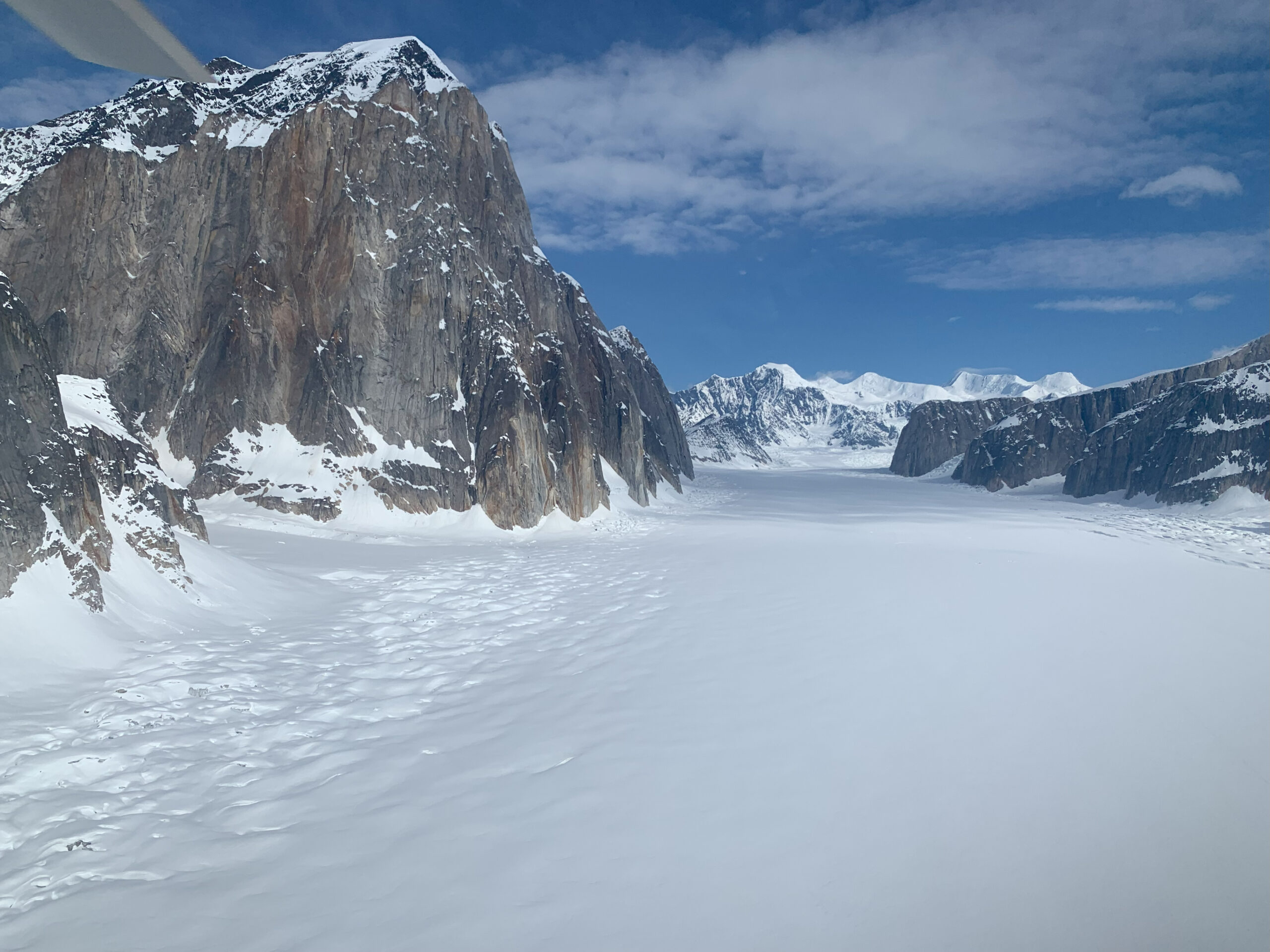 A snow-covered glacier beneath a shear rock wall.