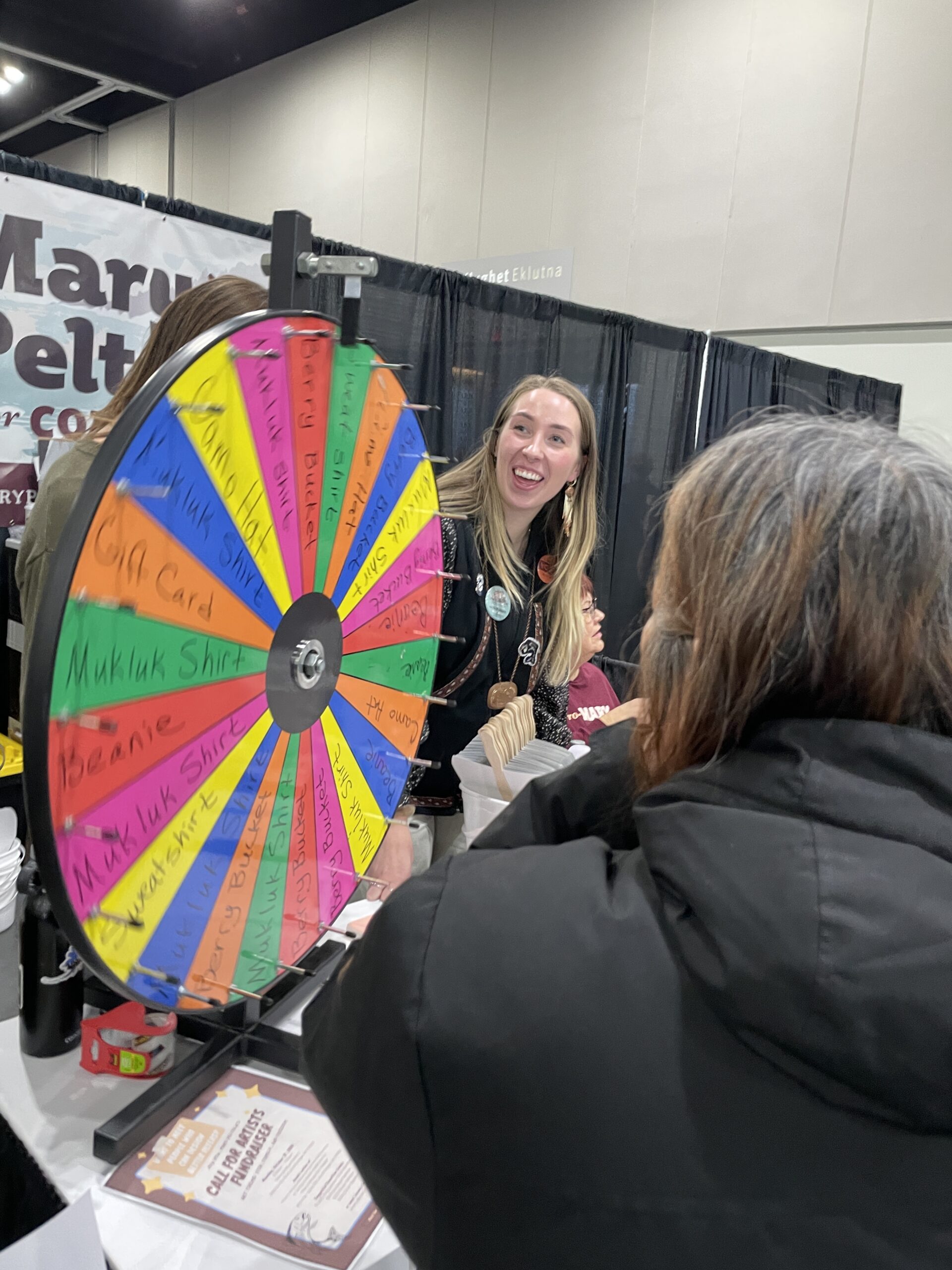 Woman smiling near colorful prize wheel