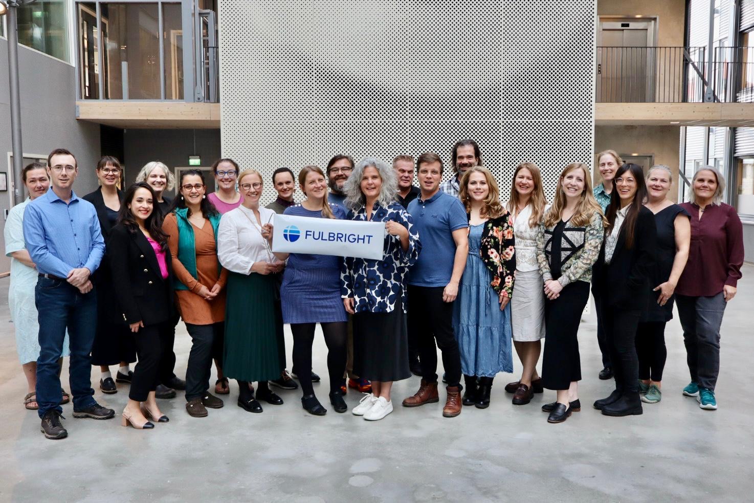 A group of people smile with a sign in the middle of the group that says "Fulbright."