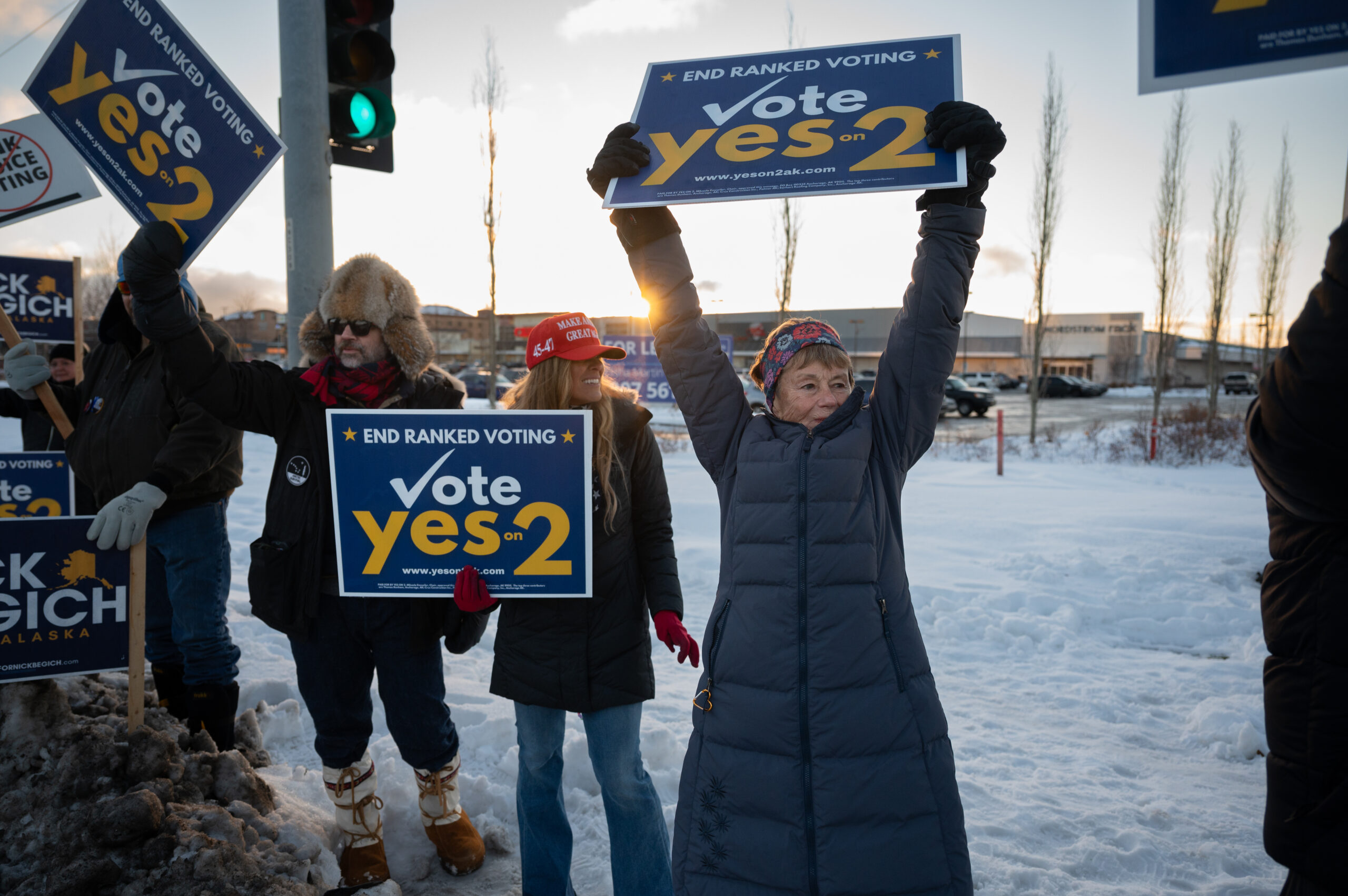 A woman in a dark blue coat waves a sign.