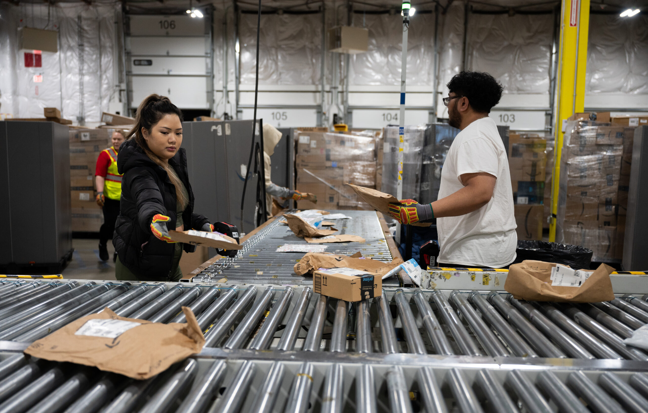 a man and a woman in a warehouse sorting brown packages