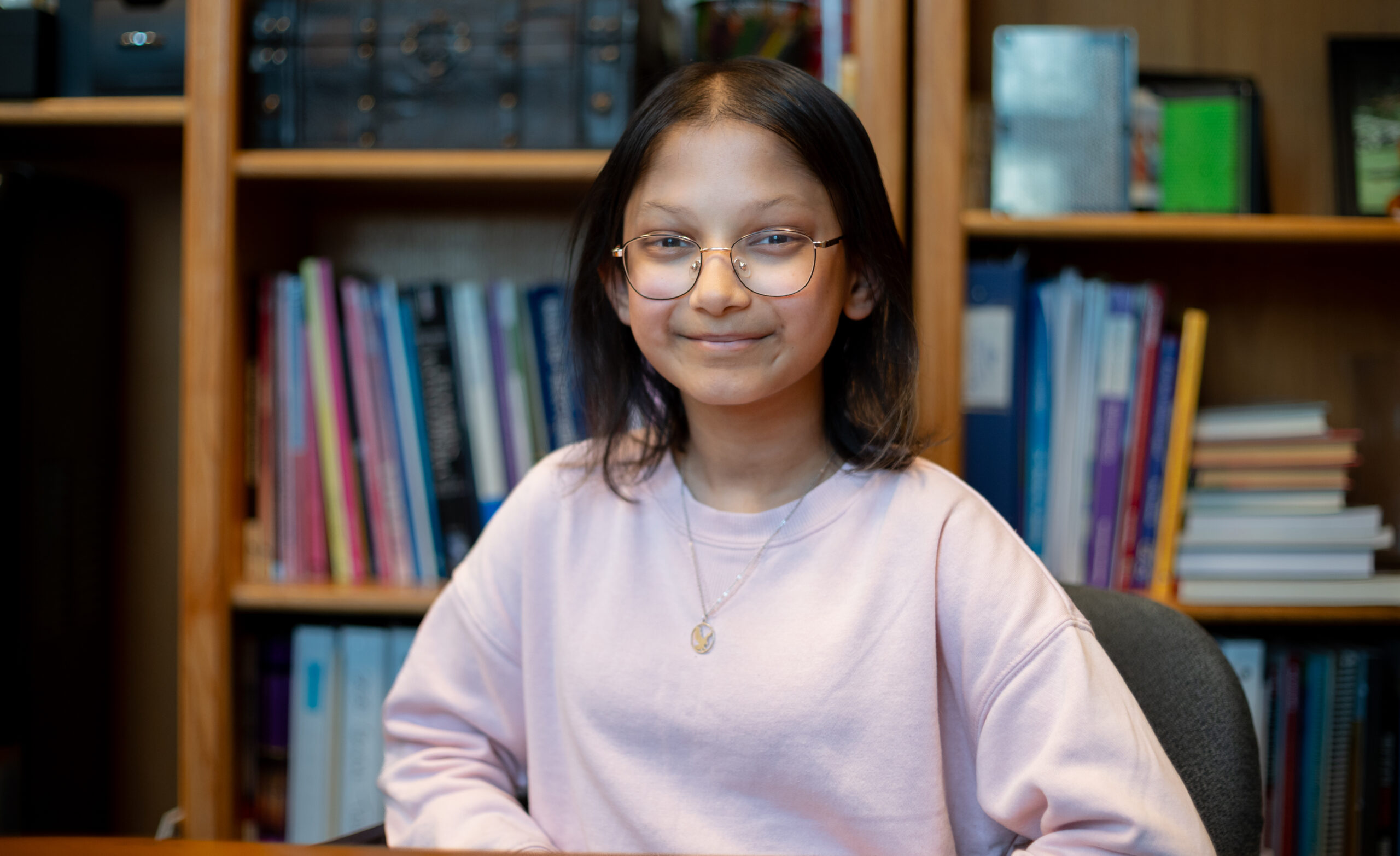 A girl with glasses and a pink sweater.