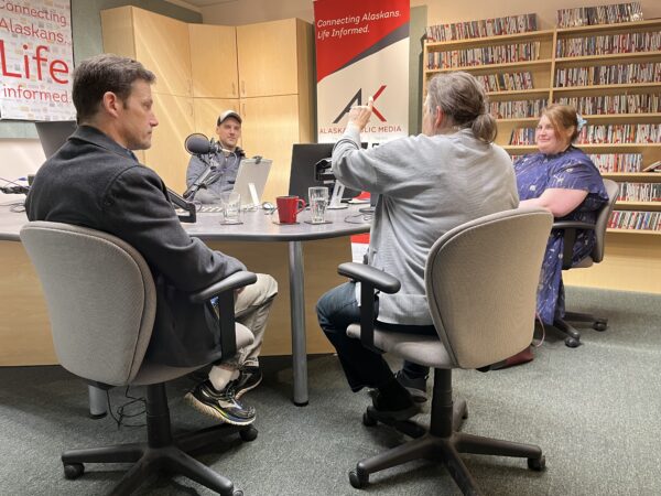 Four people sit in a radio studio.